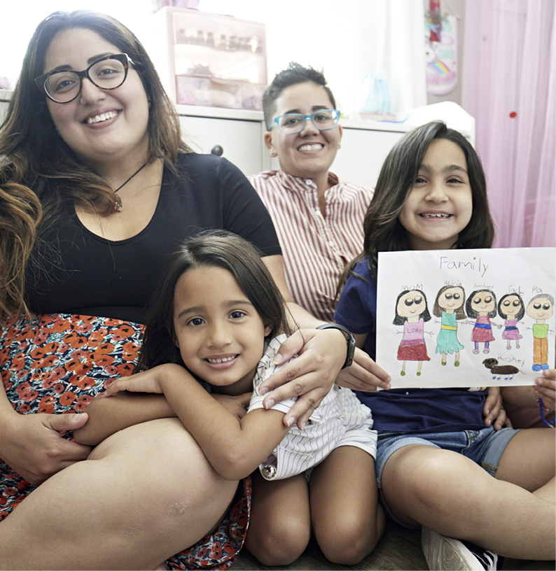 Same-sex couple sitting on floor with their young girls