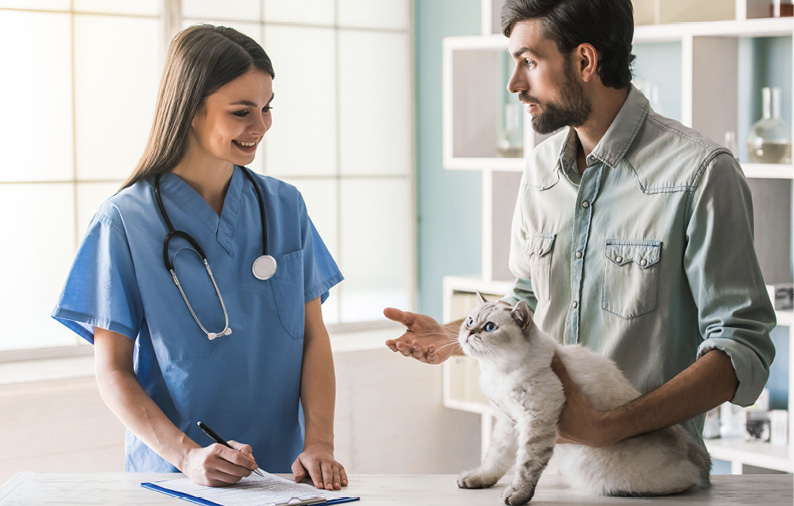 A tech talking with a cat owner and recording information, which is vital to disease management.