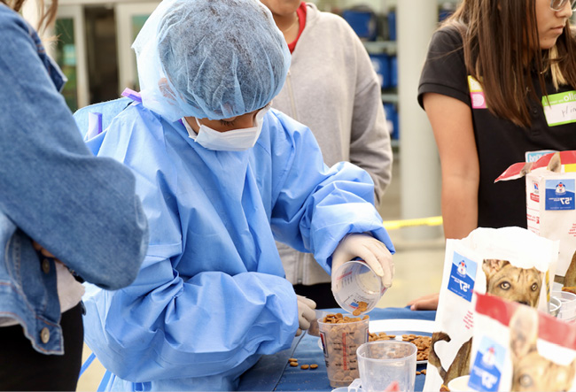 Student measuring pet food at a blendVET event