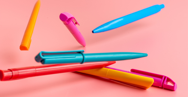 Multicolored pens on a pink background