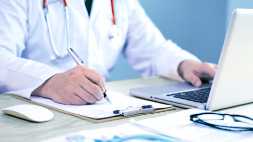 Vet sitting at laptop writing notes