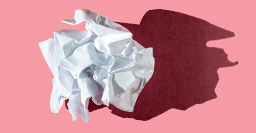 A crumpled piece of paper on a pink background