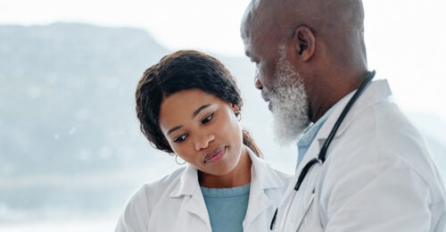 Image of an older veterinarian mentoring a younger veterinarian.