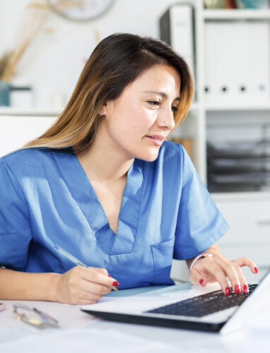 woman in scrubs at desk