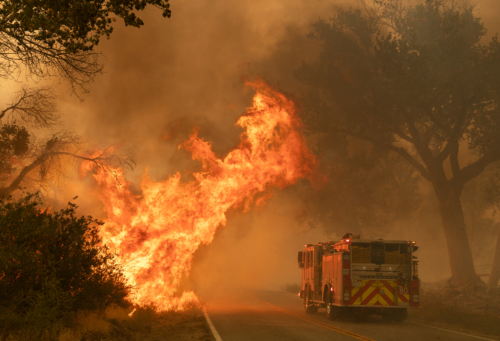 Photo of a fire truck passing flames from the California fires in 2024