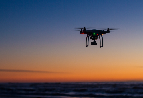 small drone in the sky at sunset