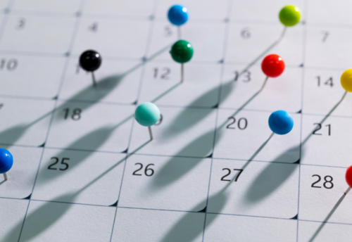 This image features multicolored thumbtacks on a plain white calendar