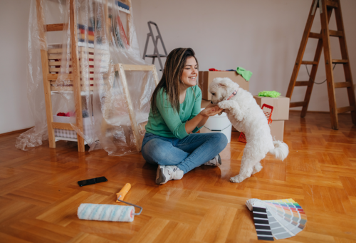 pet owner playing with white dog in room she is about to paint