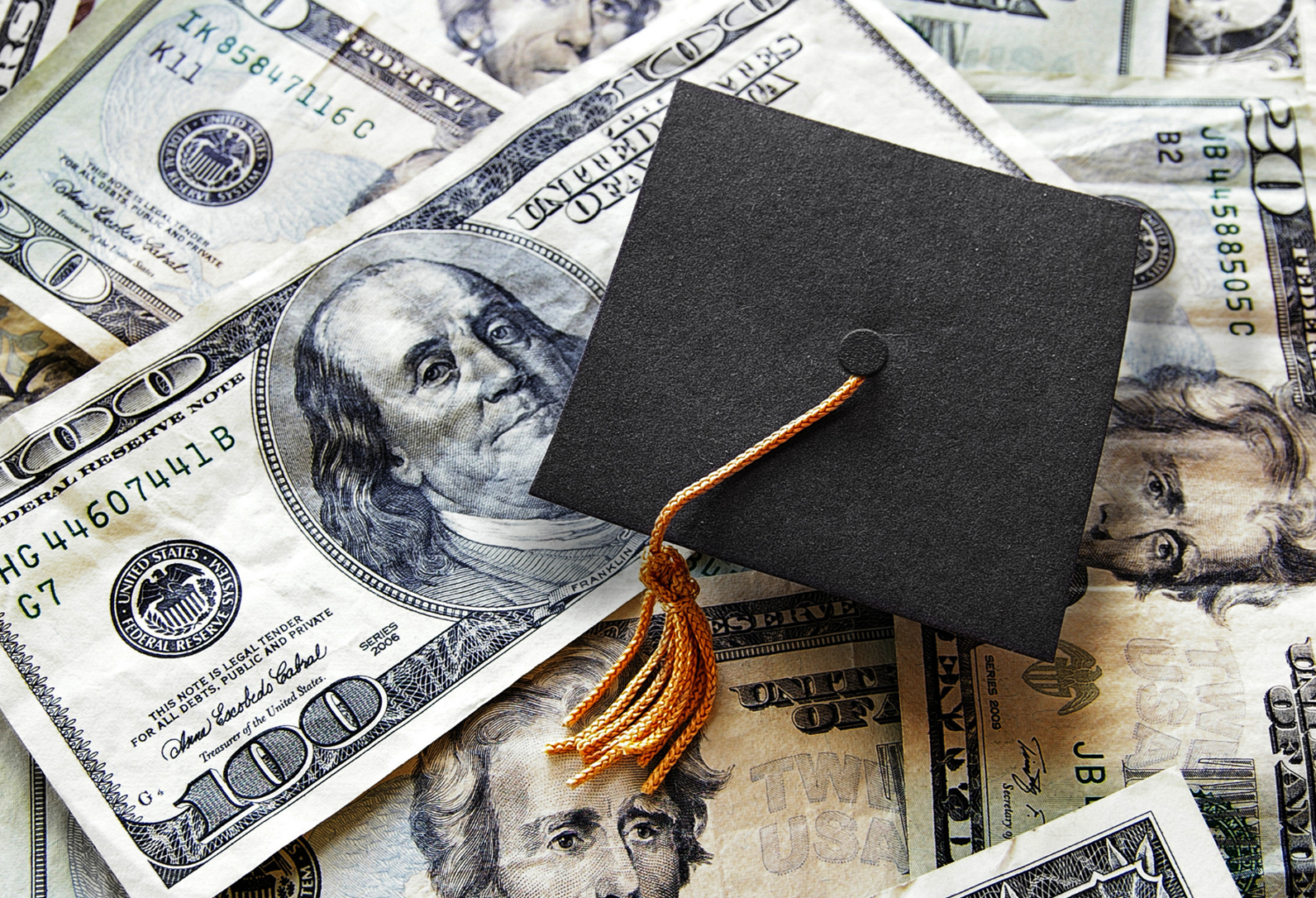 graduation cap on top of pile of money