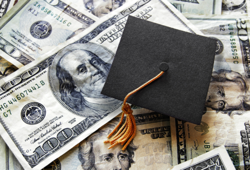 graduation cap on top of pile of money