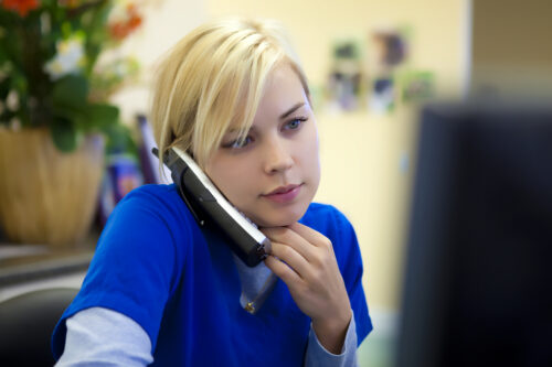 A veterinary assistant fields a question from a client.