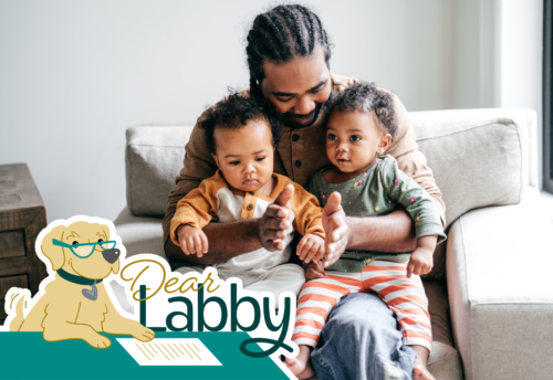 A man holds his two children in his lap. The text 
