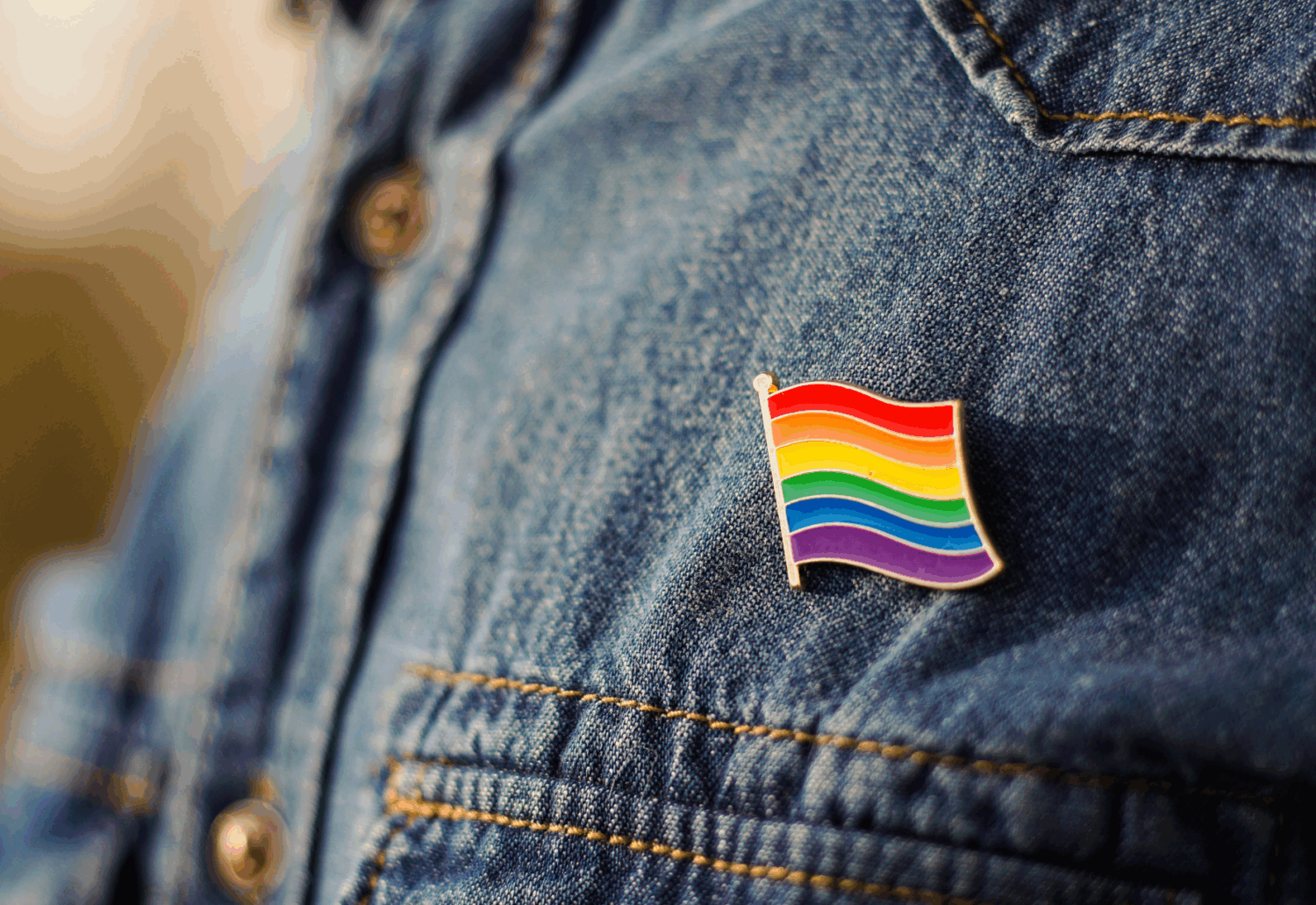 A Pride flag is pinned to a denim shirt
