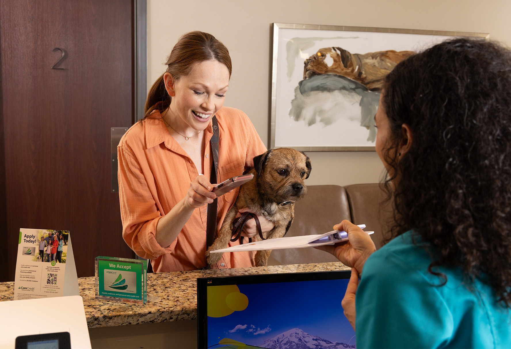 Owner holding puppy checking into vet