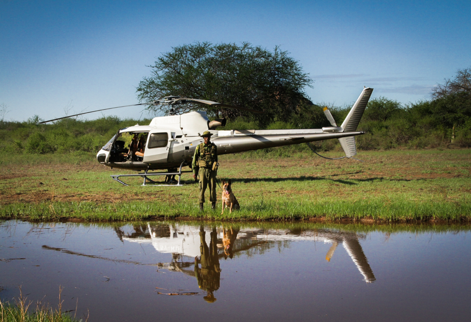 Ranger and Sheldrick Wildlife Trust Canine Unit pose with helicopter in Kenya