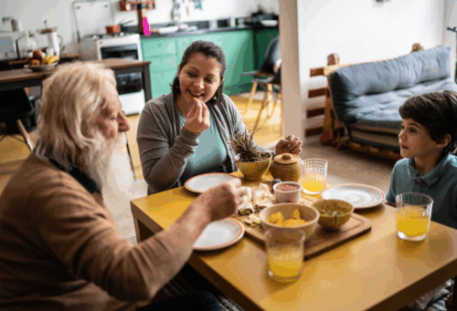Three generations sit around a table eating a meal