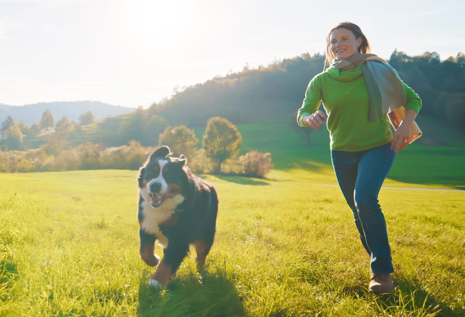 woman running with her dog outside on green grass