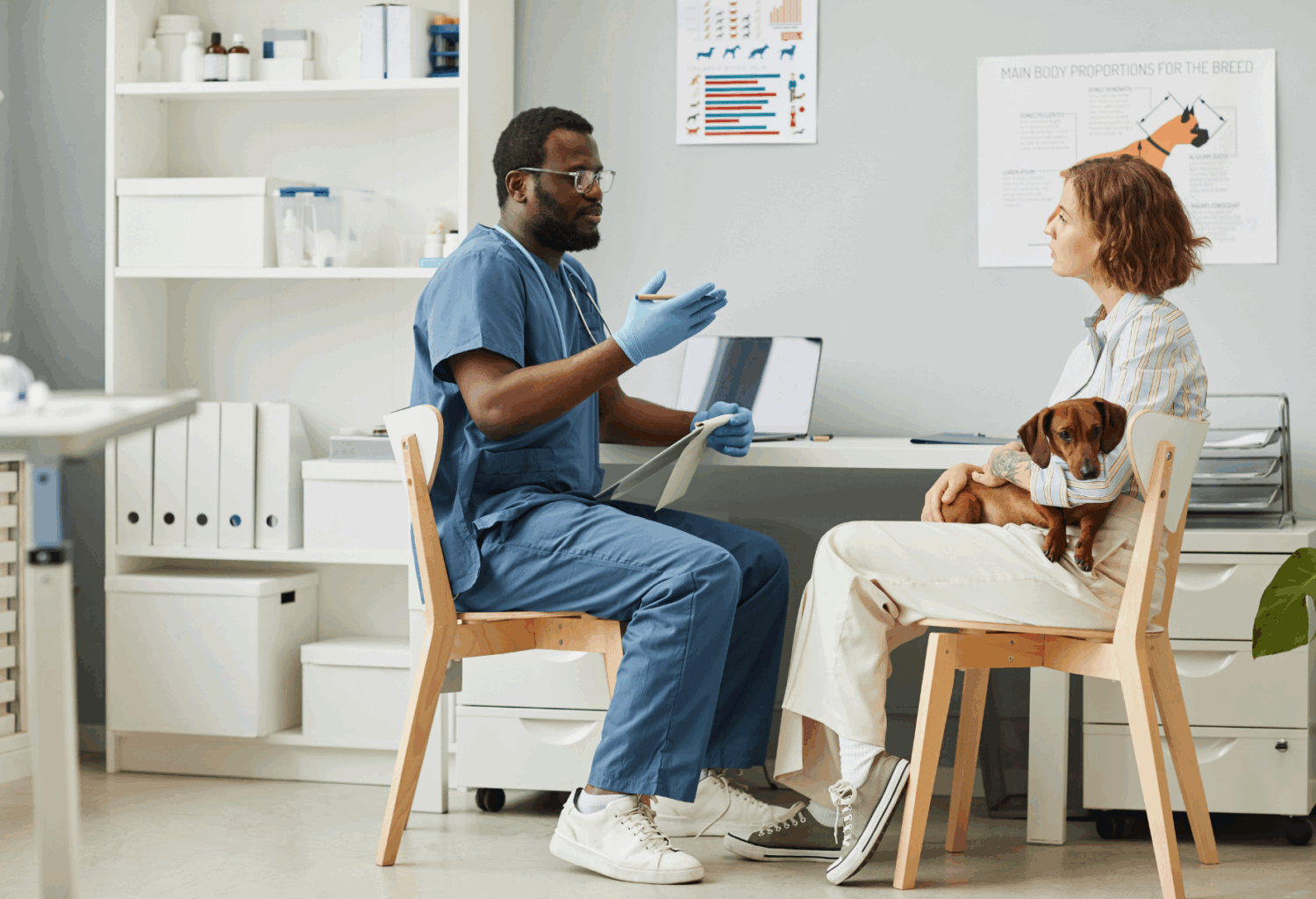 Young Black male veterinarian talks to female client and her dog