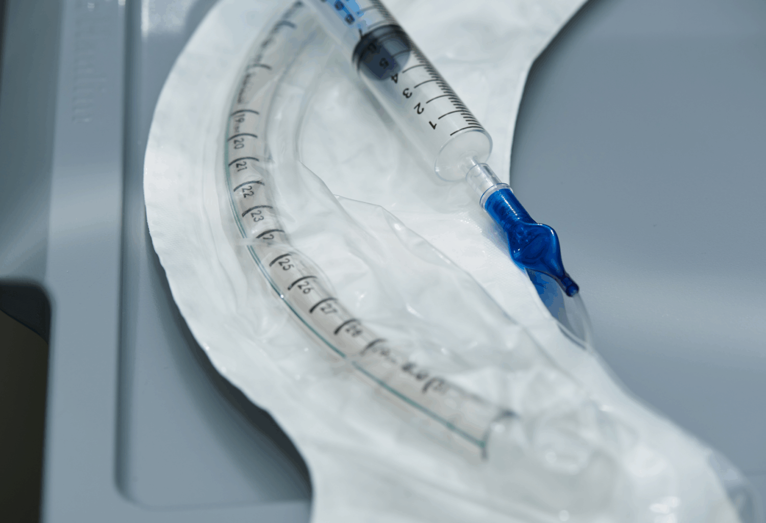An endotracheal tube and a syringe lying on a tray