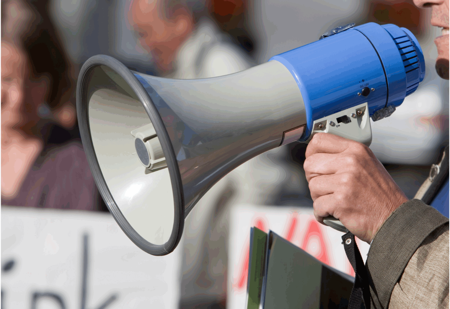 A man holds a megaphone in front of a crowd of protesters