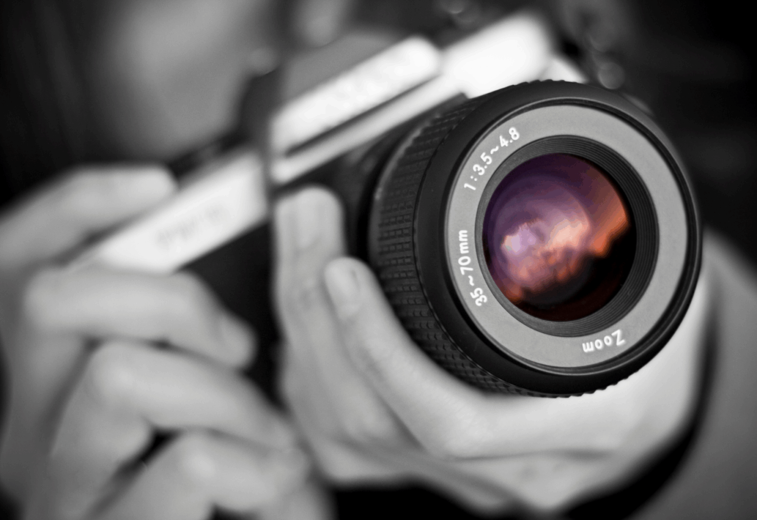 A grayscale photo of a camera in a man's hands