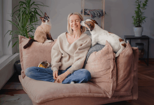 woman with a dog, cat, and Guinea pig on a couch with her