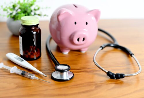 piggy bank and medical equipment such as stethoscope lined up on the desk