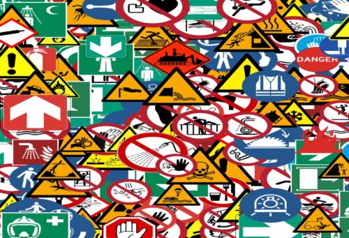 many safety and caution signs for people and workers in dangerous places or situations