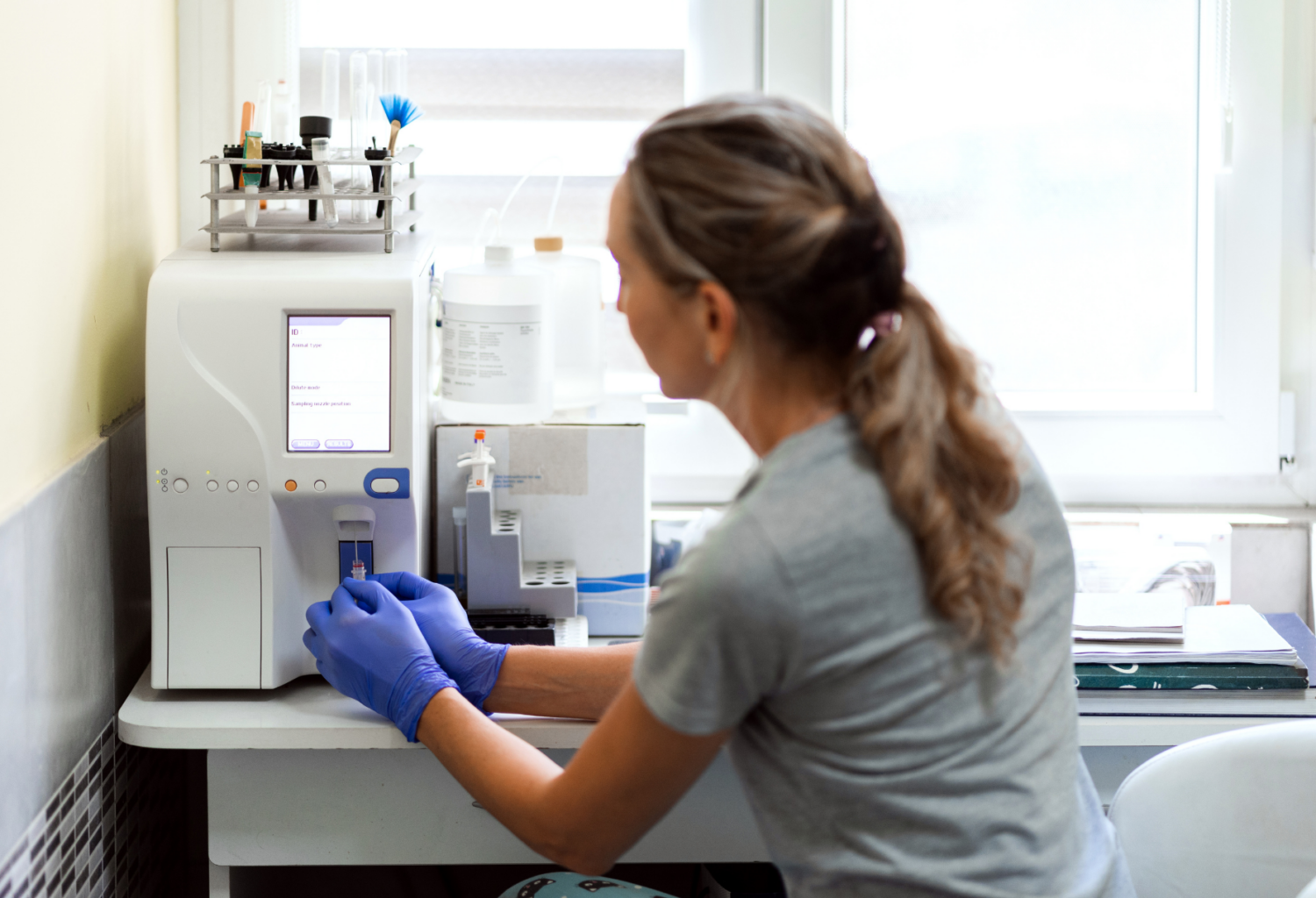 A female veterinary professional holding a blood tube in front of a machine for analysis