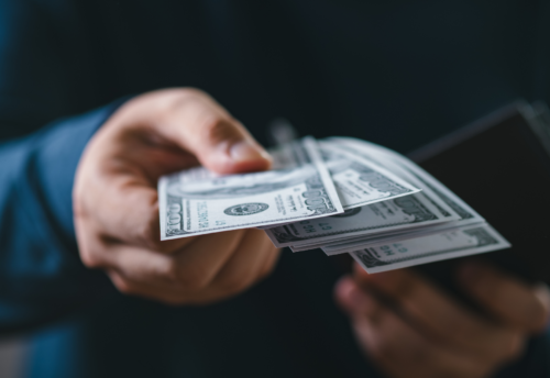 A man is handing out multiple hundred dollar bills.