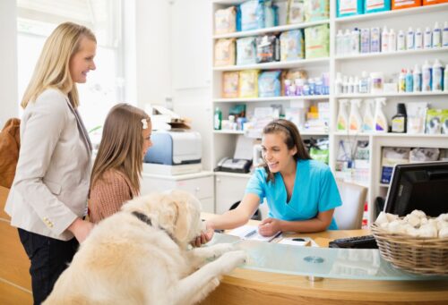 veterinary receptionist welcomes family with dog